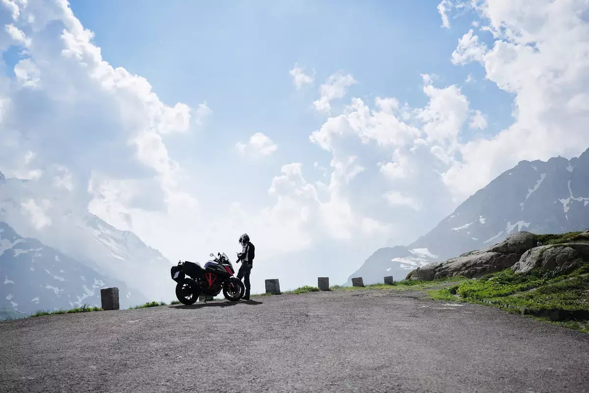 A rider standing next to his motorcycle at a scenic overlook.