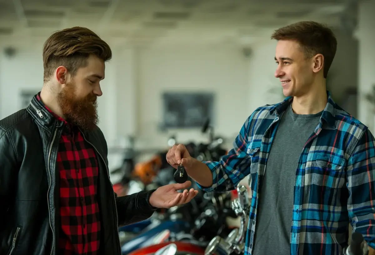 A young man receiving his keys after successfully financing a Harley.
