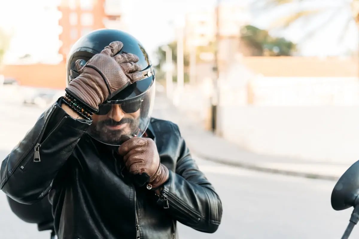 Bearded biker adjusting his helmet and gloves, preparing for a motorcycle ride in the city