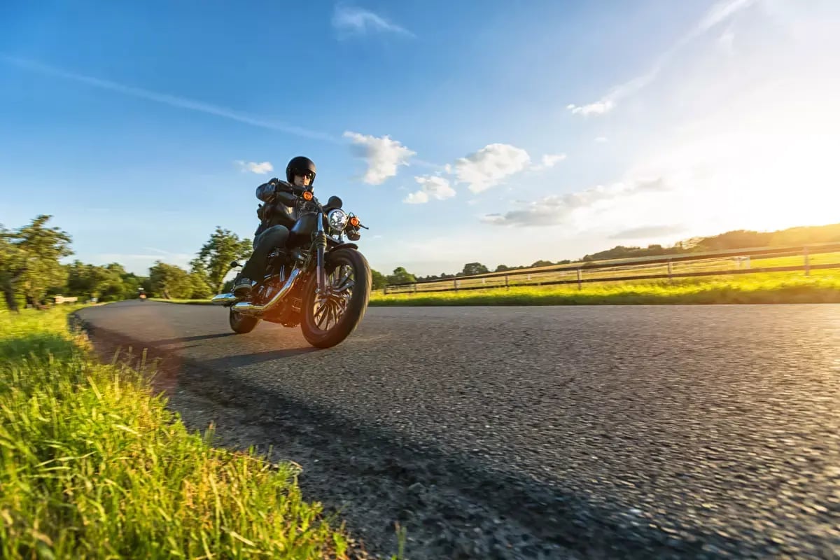 Dark motorbiker riding high power motorbike in nature with beautiful sunset light