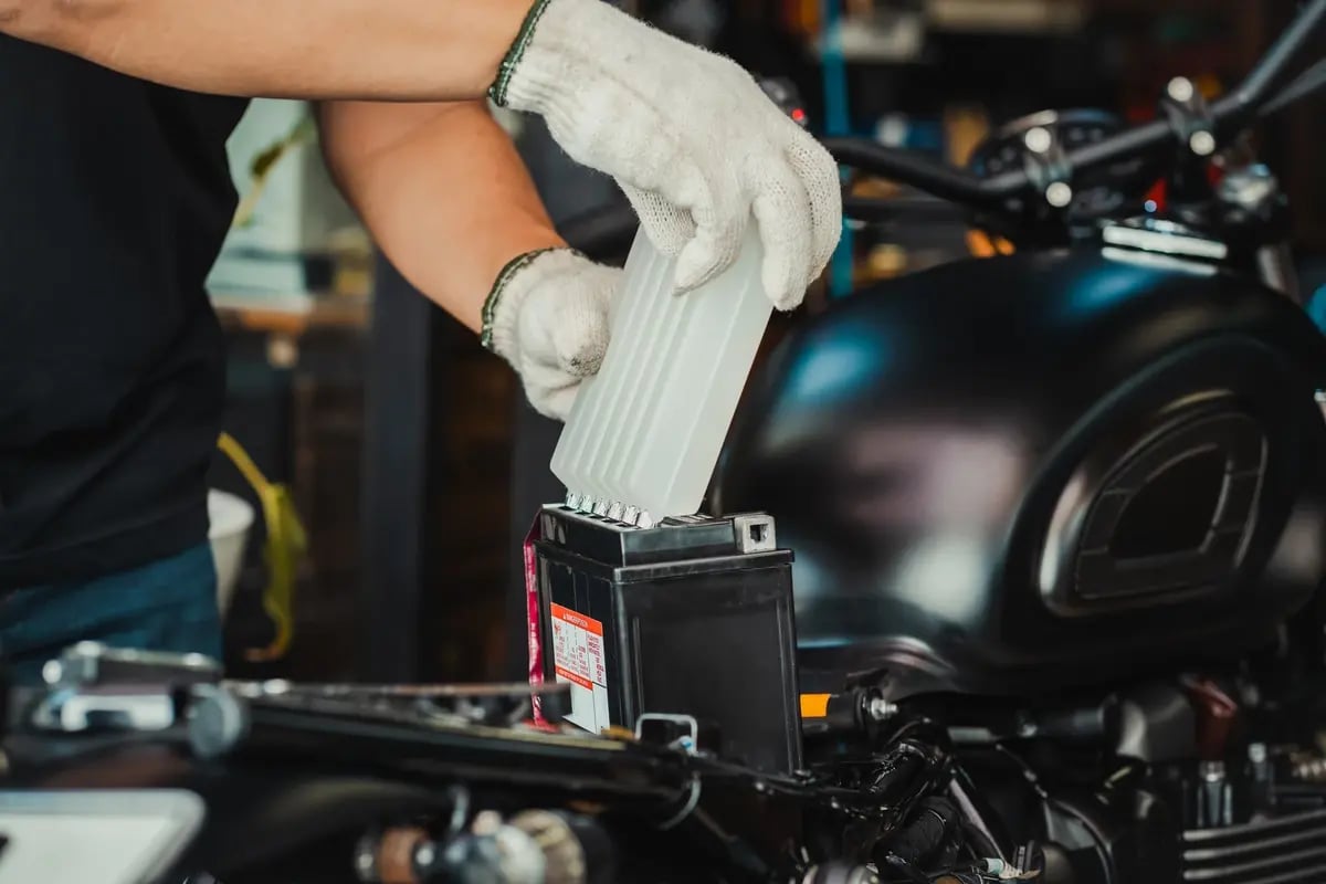 Mechanic replaces motorcycle battery and holding Acid pack or sealed battery electrolyte pack to prepare for fill up