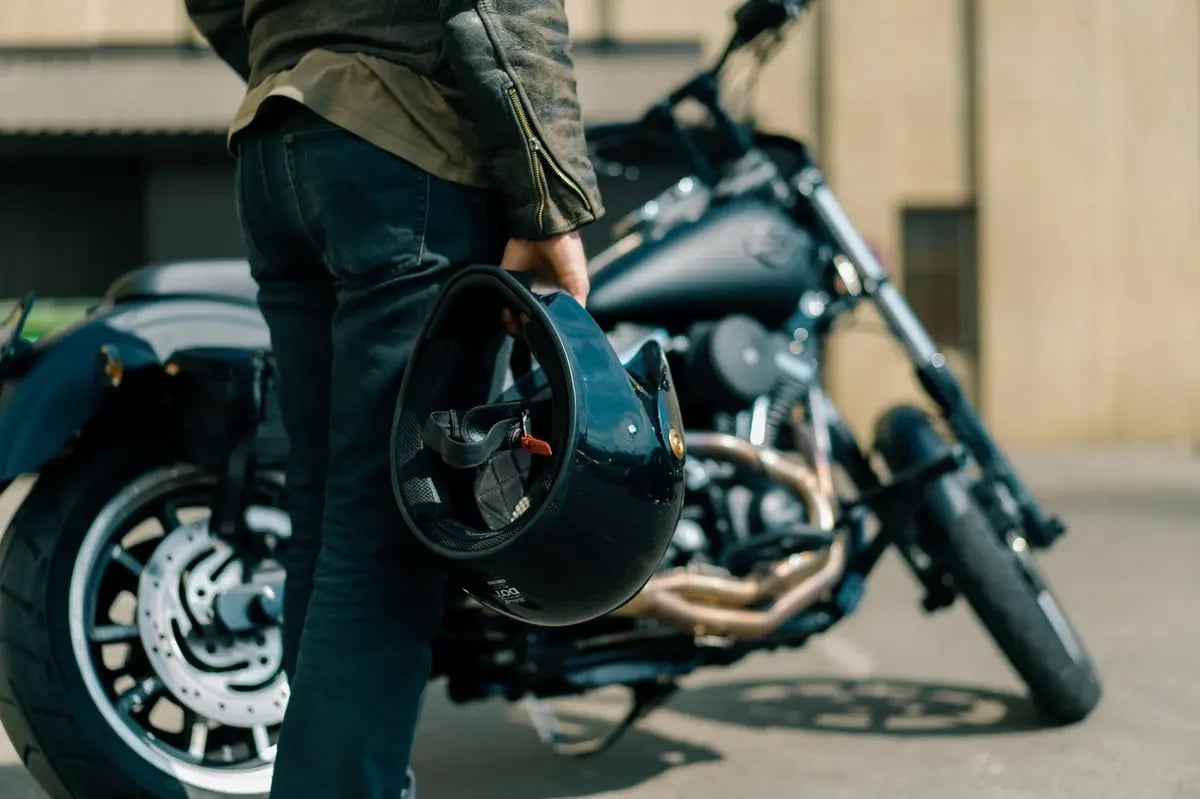 Motorcycle rider standing in front of a bike holding a helmet