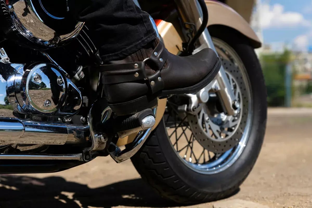 Motorcycle rider’s foot in boots on the brake lever.