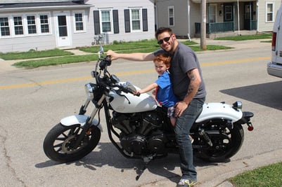 A man and his young son sitting on a white Yamaha Bolt motorcycle