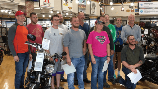 A group of Harley Davidson Riding Academy students posing for a photo after graduating the class.